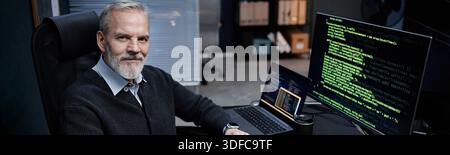 Portrait of Middle Aged Caucasian Man Working with Code on Computer Screens Stock Photo