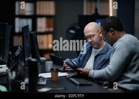 Middle Aged Caucasian Man and Young Black Man Collaborating in Office Stock Photo