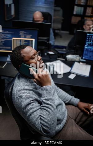 Young Adult Black Man Talking on Smartphone While Working in Office Stock Photo