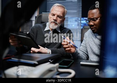 Middle Aged Caucasian Man and Young Black Man Analyzing Data on Tablet Stock Photo
