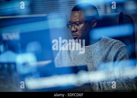 Young Adult Black Man Concentrating While Reviewing Security Data on Computer Stock Photo