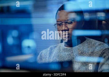 Young Adult Black Man Focusing on Computer Screen While Working in Office Stock Photo