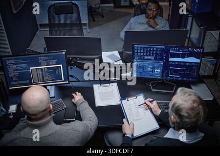 Middle Aged Caucasian Men and Black Man Analyzing Cybersecurity Data in Office Stock Photo
