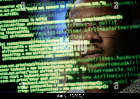 Portrait of Young Adult Black Man Analyzing Code Reflected on Computer Screen Stock Photo