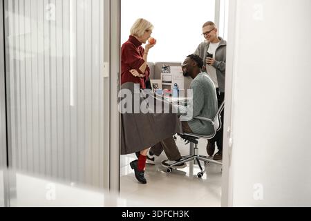 Young Caucasian Woman Talking with Young Black Man and Caucasian Man in Office Stock Photo