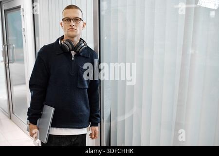 Portrait of Young Adult Caucasian Man Holding Laptop and Wearing Headphones Stock Photo
