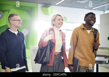 Multiethnic Young Adults Arriving at Modern Office and Smiling Together Stock Photo