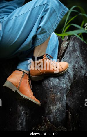 Close-Up of a Woman’s Boots Resting on a Tree Stump Stock Photo
