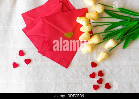 Composition of red envelopes with heart seals yellow tulips and decorative hearts Stock Photo