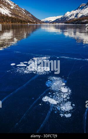 Trapped methane bubbles under the frozen lake with landscape as background Stock Photo