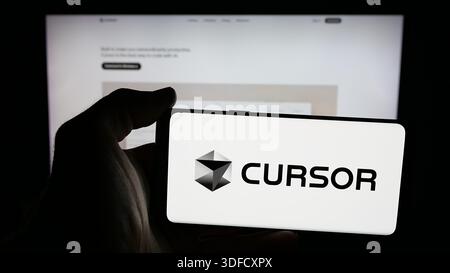 December 3, 2025, Germany: In this photo illustration, a person is holding a mobile phone with the logo of ai software company Cursor (Anysphere Inc.) on screen in front of web page. (Credit Image: © Timon Schneider/SOPA Images via ZUMA Press Wire) EDITORIAL USAGE ONLY! Not for Commercial USAGE! Stock Photo