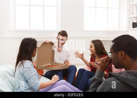 Students sharing pizza at home party Stock Photo