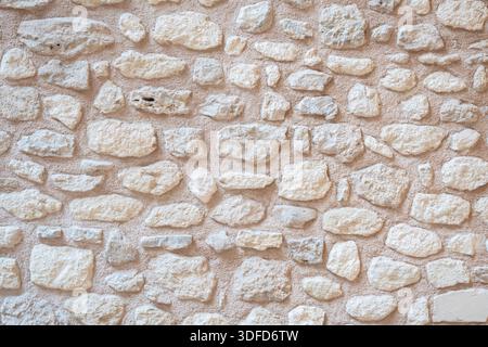 Rustic stone wall texture forming natural architectural background with rough beige and light brown rocks and aged mortar pattern Stock Photo