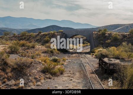 Train tracks going through short tunnel bridge in desert landscape Stock Photo