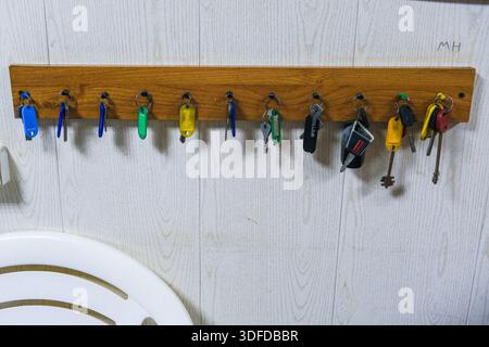 Russia, Saint Petersburg, 11.01.2026 Key storage with many different keys hanging on a wooden rack. Home organization system for hanging keys and smal Stock Photo