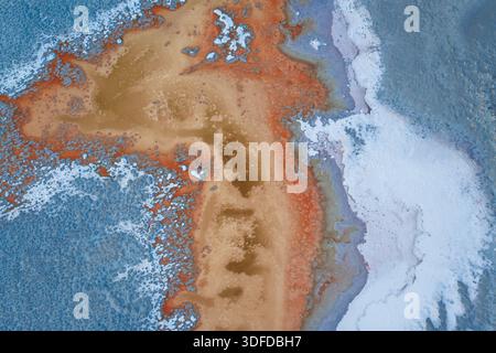 Aerial view of the land displaying a symphony of earthy tones, where rust-colored minerals paint a stark contrast against the cool, icy blues of the w Stock Photo