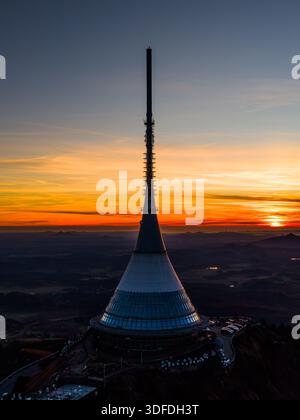 The image shows Jested mountain and hotel during sunset. The aerial view highlights the structure against the vibrant sky. The scene captures the beauty of the evening in Liberec. Stock Photo