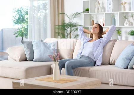 Serious and relaxed woman in blue resting sitting on a couch at home Stock Photo