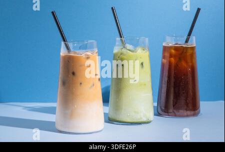 Three iced beverages served in clear glasses on a clean, minimal studio background, including a matcha latte, an iced coffee and iced latte. Stock Photo