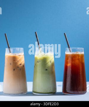 Three iced beverages served in clear glasses on a clean, minimal studio background, including a matcha latte, an iced coffee and iced latte. Stock Photo