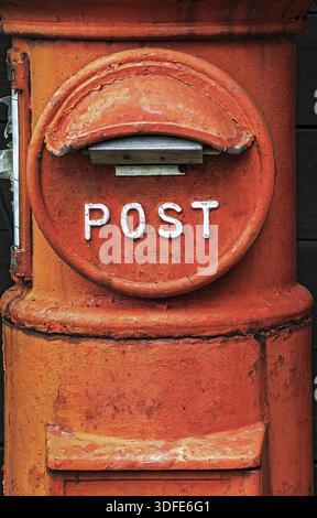 A historic orange letter box. The old red post box pillar close up. The ancient round mailbox Stock Photo