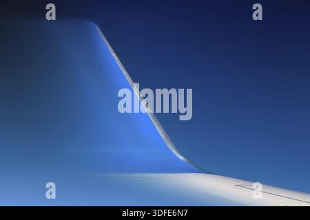 Part of fast moving jet wing, close view. The blurred winglet on a wing of plane when a flight in a blue sky Stock Photo