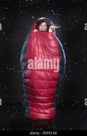 Young beautiful woman in the sleeping bag on a black studio background Stock Photo