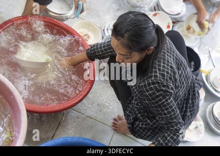 Woman washes dishes in a basin on the floor Stock Photo