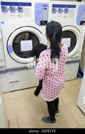 Young woman doing laundry in the laundry room Stock Photo