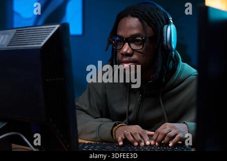 Young Black Man Wearing Headphones Using Computer While Concentrating Stock Photo