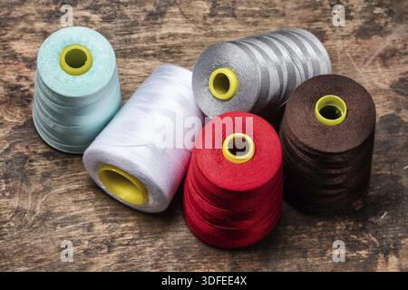 Bobbins of coloured threads on a wooden table Stock Photo