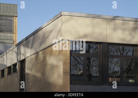 Borken, NRW, German Building architecture showing brick and concrete walls with tree reflections on windows under a blue sky Stock Photo