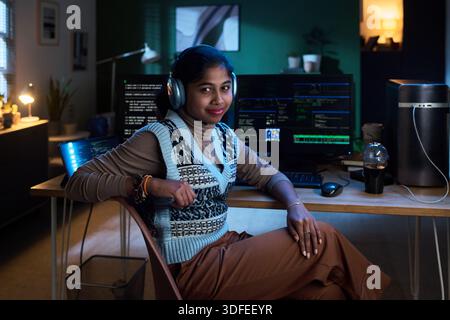 Portrait of Young South Asian Woman Listening to Music While Programming Stock Photo