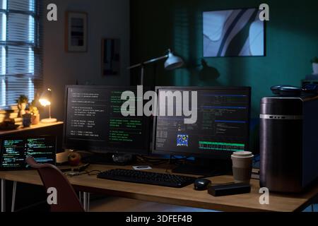 Empty Home Office Desk Featuring Multiple Monitors Displaying Programming Code Stock Photo