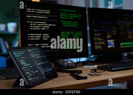Close up of Tablet and Monitors Displaying Programming Code in Office Stock Photo