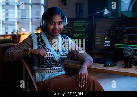 Portrait of Young South Asian Woman Wearing Headphones Working at Computer Stock Photo
