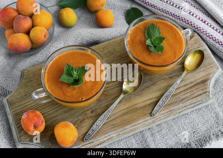 Two cups of smoothie, apricots and a yoghurt and mint leaves. The view from the top Stock Photo