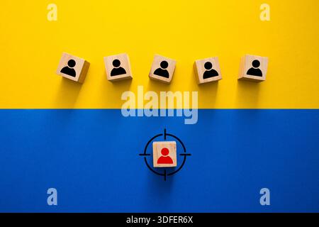 Wooden blocks with person icons showing a red target on one individual Stock Photo