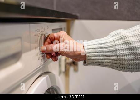 Senior woman's hand turning on the washing machine Stock Photo