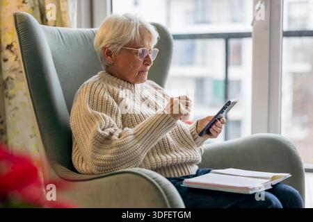 Senior woman using written notes and mobile phone Stock Photo
