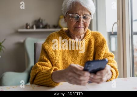 Senior woman using smart phone at home Stock Photo