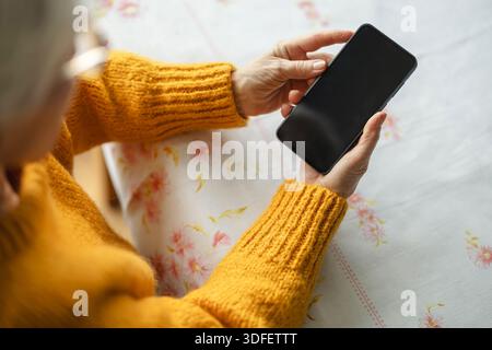Senior woman using smart phone at home Stock Photo