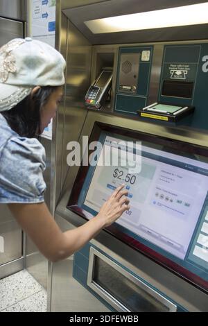 A young woman buys a public transport ticket in a vending machine ...