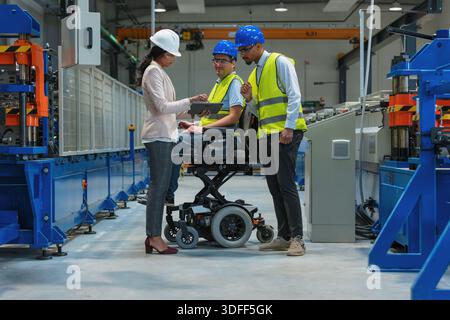 Female manager oversees production as workers with diverse backgrounds and disability collaborate in a factory setting focused on teamwork and Stock Photo