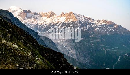 Snow-capped mountain range with rugged peaks and green slopes. Stock Photo
