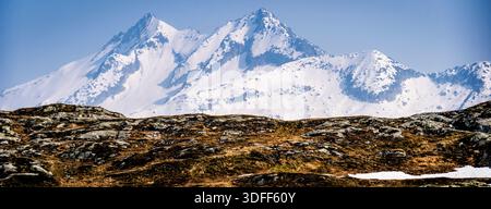 Snow-covered mountain peaks under a clear blue sky. Stock Photo