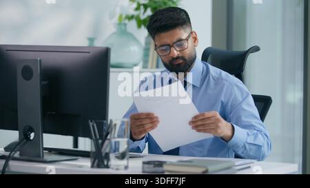 Indian businessman Arabian business man ethnic male worker guy professional entrepreneur working in office typing computer checking documents work Stock Photo