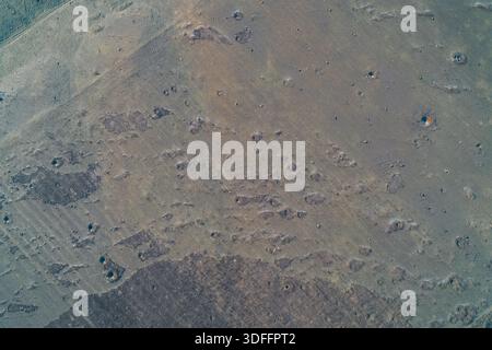 Textured earth ground with soil craters and wheel tracks next to a ...