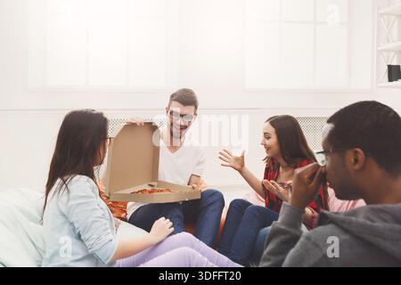 Students sharing pizza at home party Stock Photo