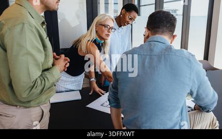 A diverse group of professionals collaborating at a table for a strategic meeting in a bright office setting, showcasing teamwork, discussion, and ali Stock Photo
